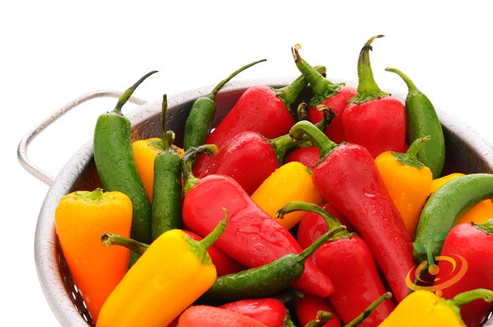 Colorful Serrano Tampiqueño peppers in red, green, and yellow in a metal colander.