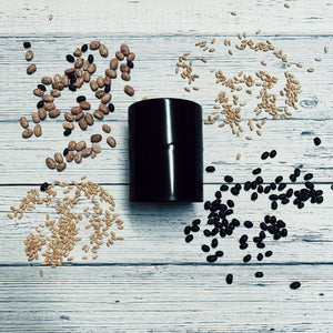 Extra-small black Seed Storage Vault surrounded by various seeds on a wooden surface